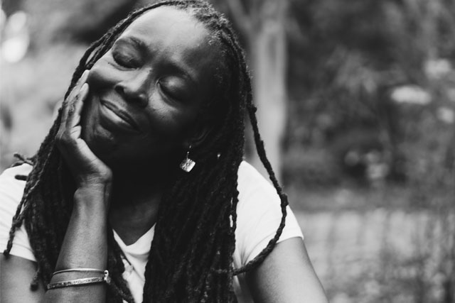 Women smiling with her eyes closed and face resting in the palm of her hand