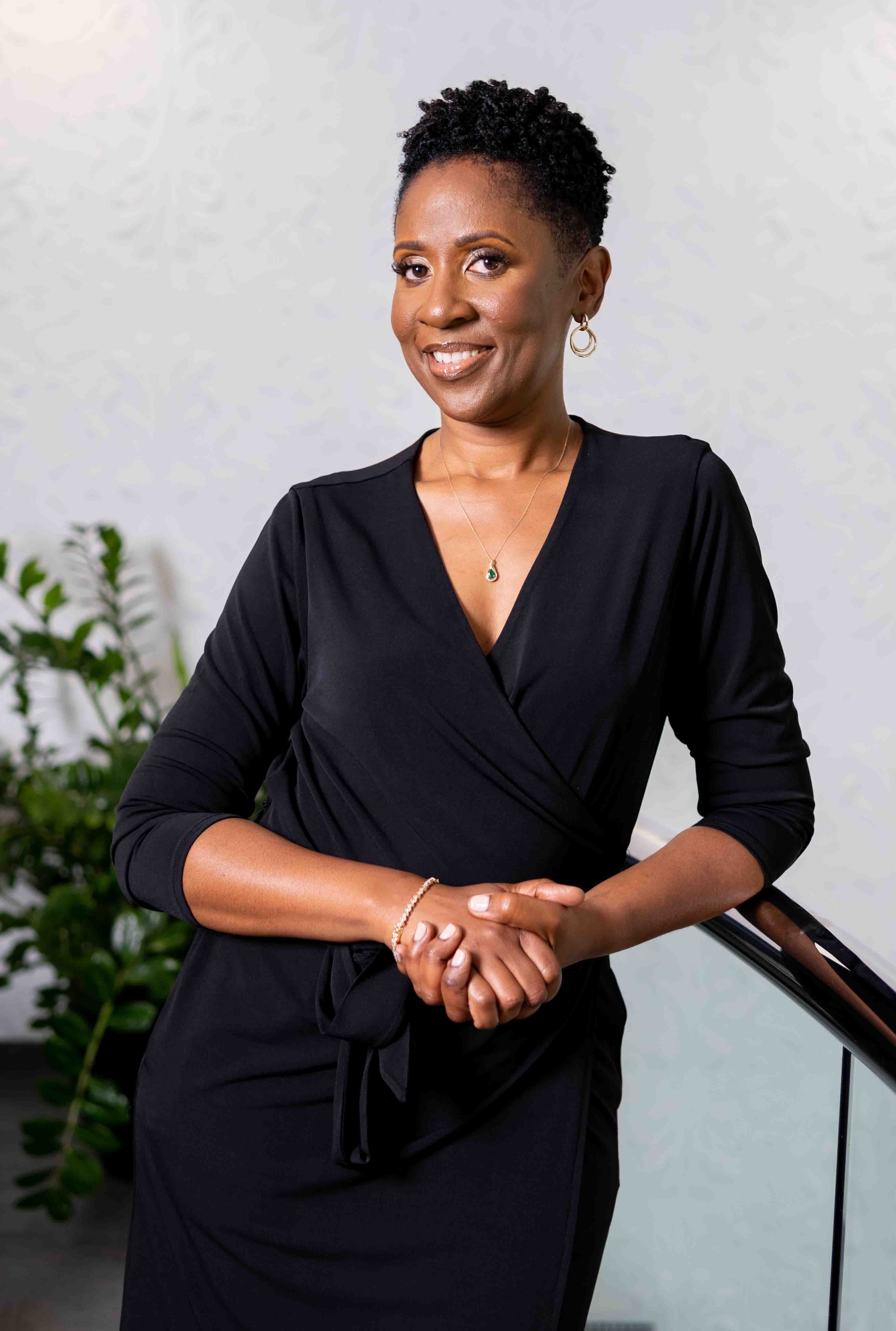 Portrait of Nicole Pride in a black dress leaning against a rail.